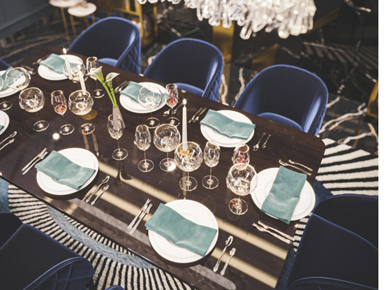 Luxury Dining Room Interior Abu Dhabi with overhead view of set dining table, teal napkins, glassware and navy velvet chairs